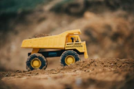 Close-up of a child’s hands gripping a bright yellow Tonka dump truck.