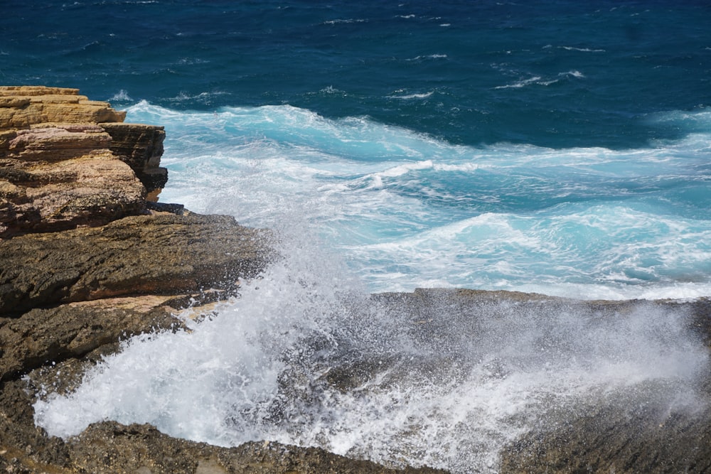 ocean waves crashing on brown rock formation during daytime