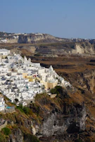 Ancient whitewashed buildings and blue domes of a Greek island against a sunny backdrop.