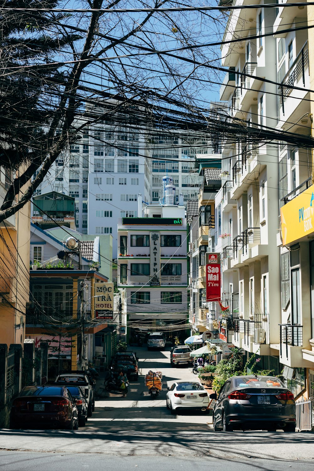 昼間は建物と建物の間の道路脇に車が停まっています