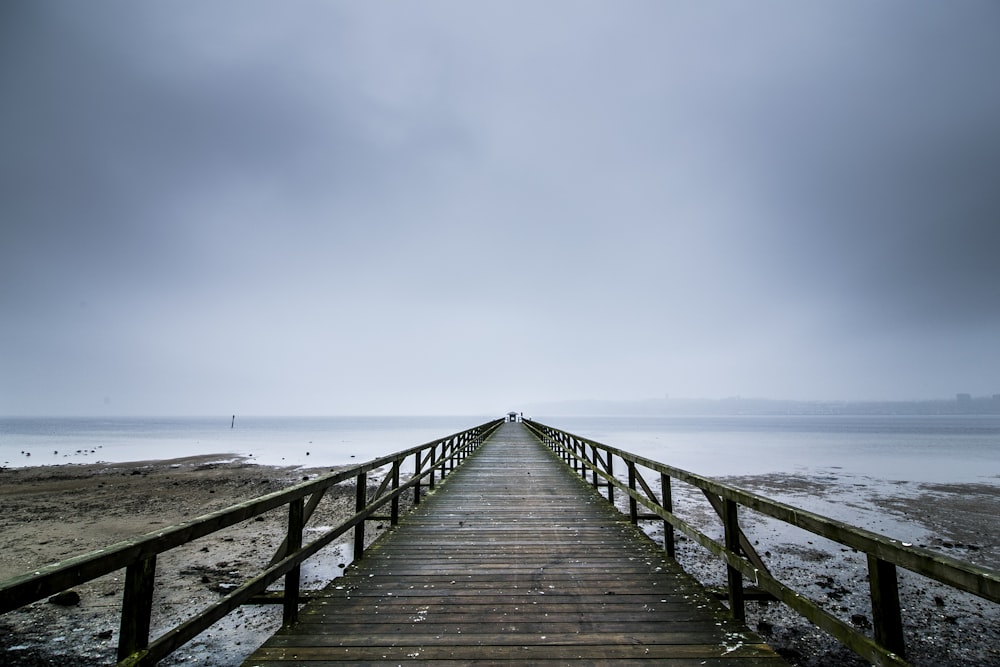 brown wooden dock on sea under blue sky during daytime