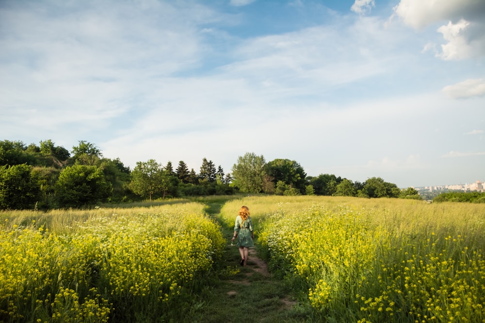 woman in white shirt walking on green grass field during daytime