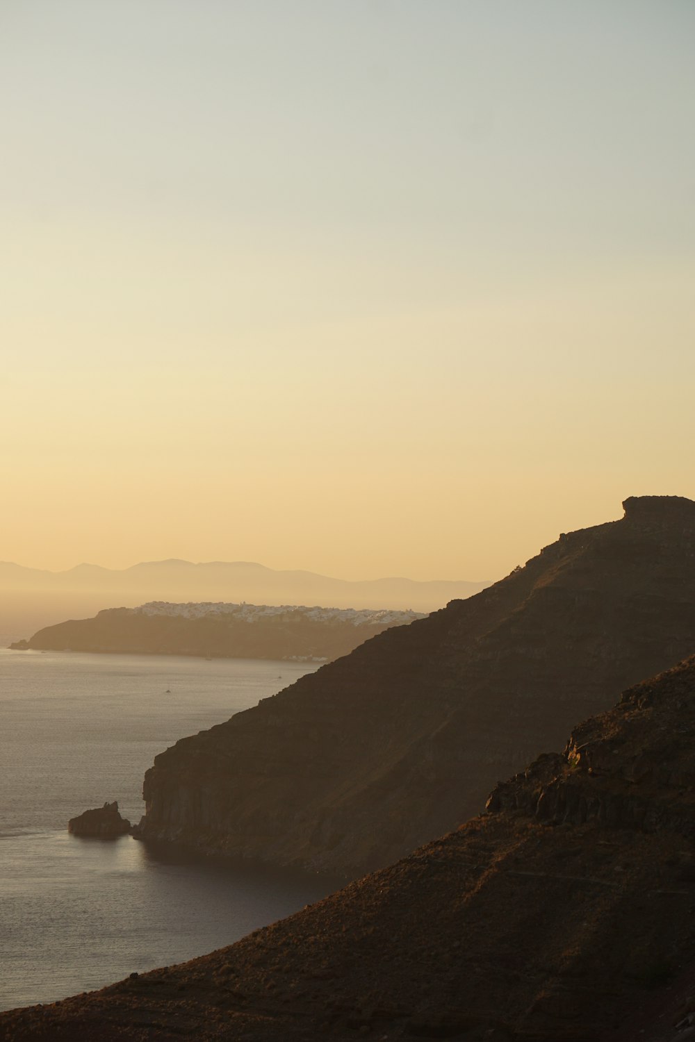 silhouette of person standing on rock formation near body of water during daytime