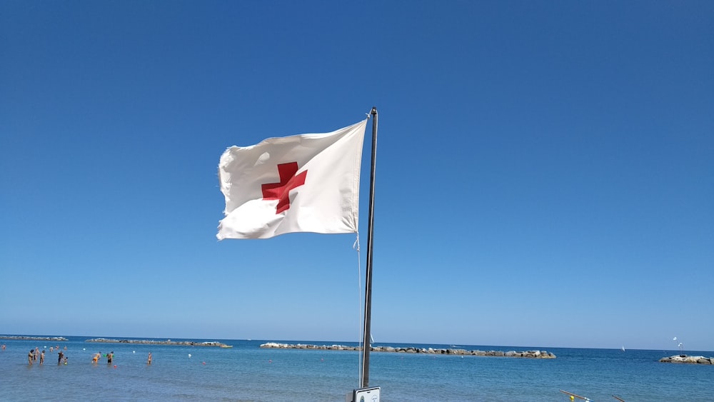 white and red flag on pole near sea during daytime
