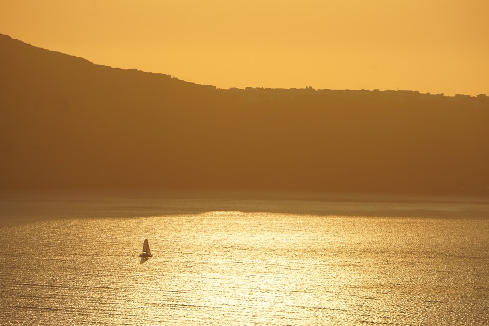 silhouette of person riding on boat on sea during sunset