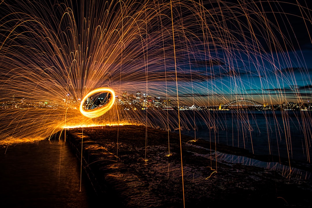 steel wool photography of person standing on bridge