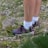 Hiker wearing wool socks standing on a rocky trail with mountains in the background.