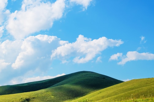 A serene landscape with a clear blue sky and green hills.