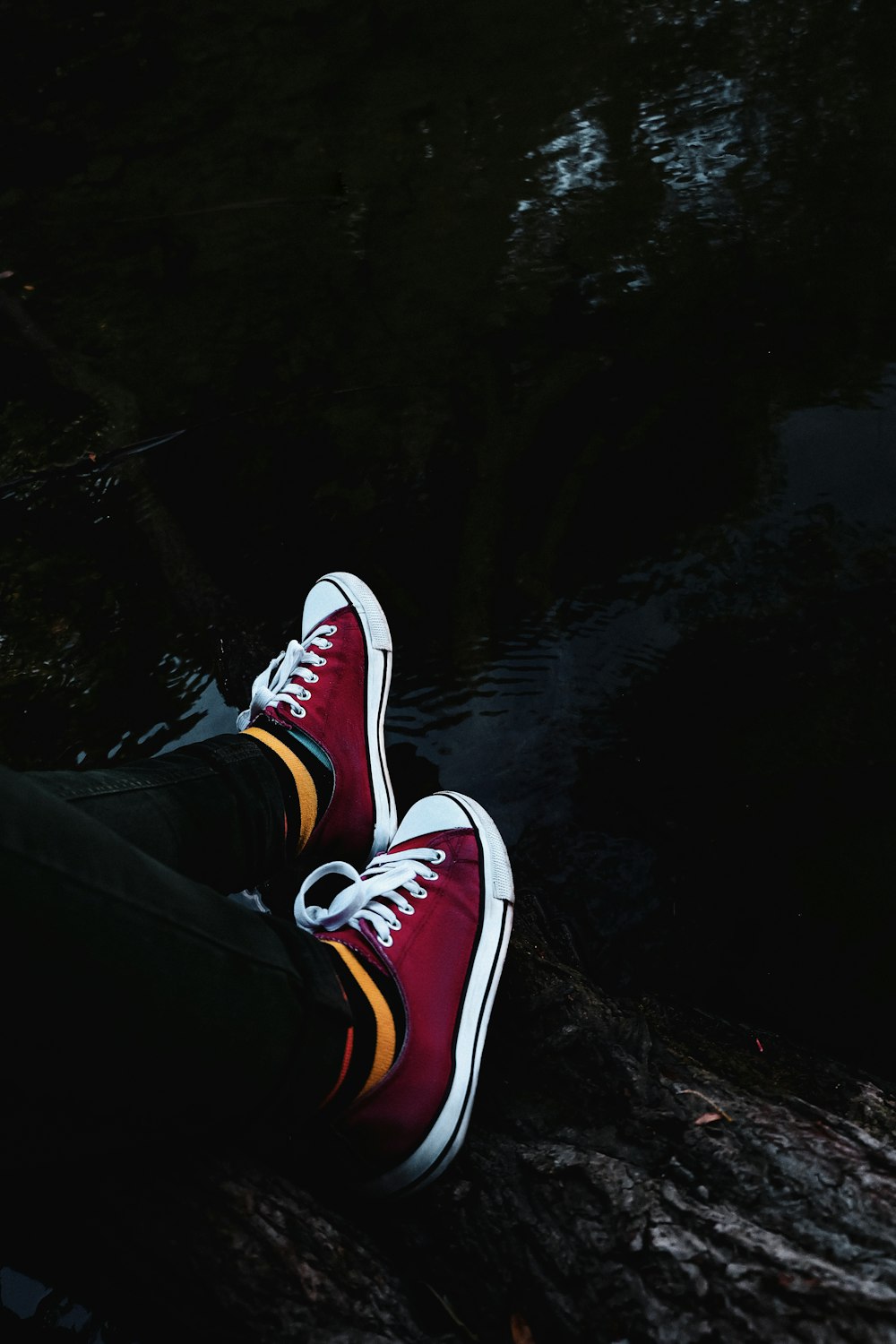 person in black pants wearing red and white sneakers