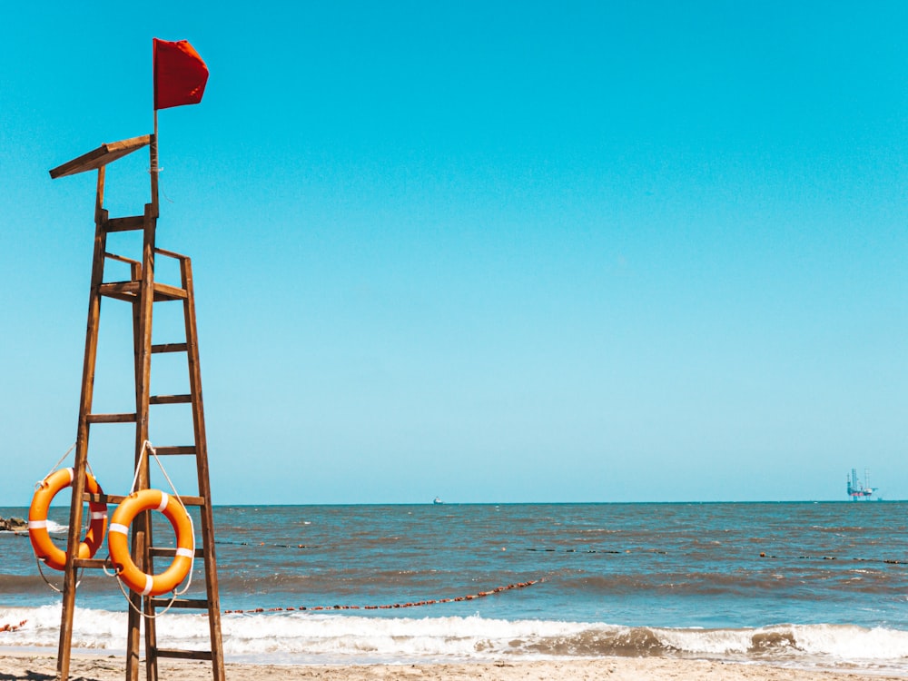 red flag on brown wooden ladder on beach during daytime