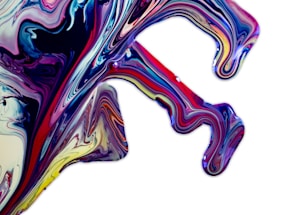 Vivid, swirling patterns of paint in shades of blue, pink, red, yellow, and purple create an abstract, fluid design on a white background. The flowing lines and curves resemble the dynamic movement of liquid.