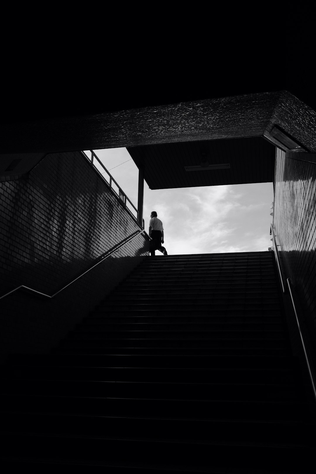 grayscale photo of man walking on stairs