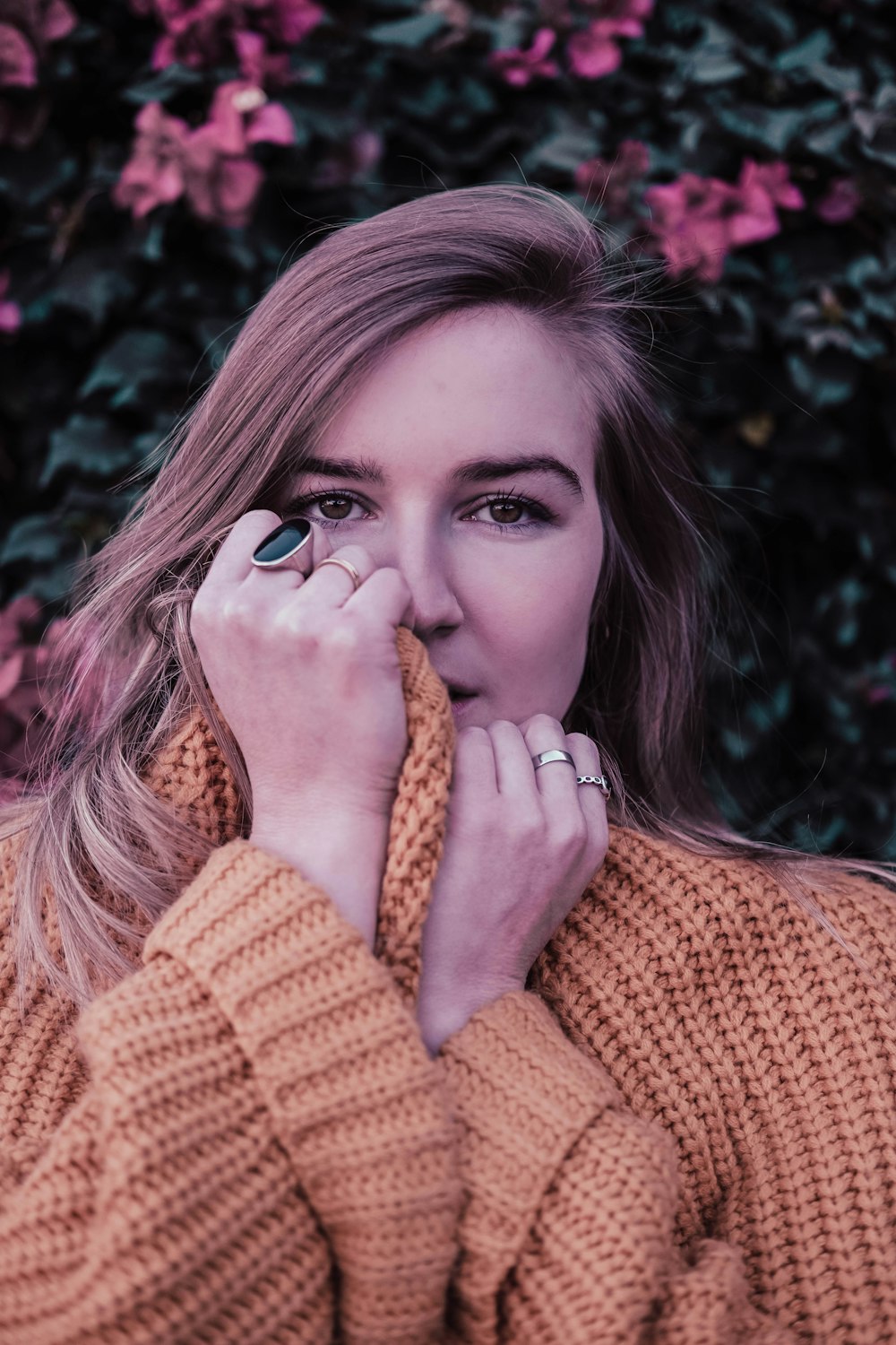 woman in brown knit sweater covering her face with her hands