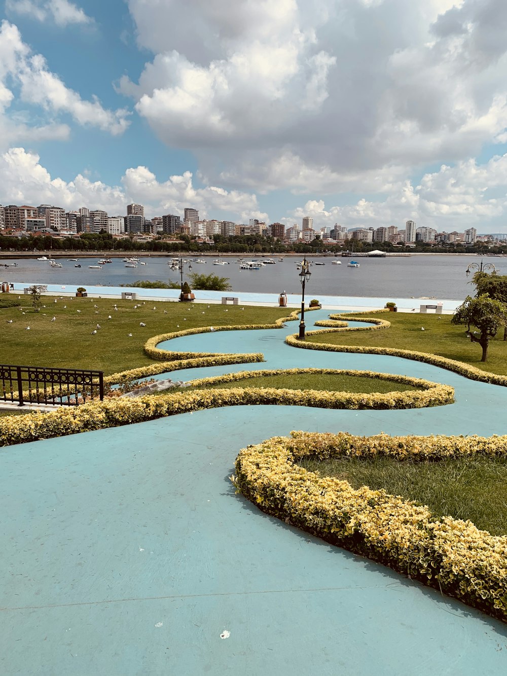 green grass field near body of water under cloudy sky during daytime