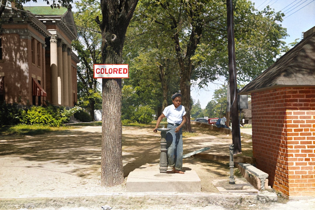 A young African American boy drinks out of a fountain labeled