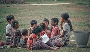 children sitting on green grass field during daytime