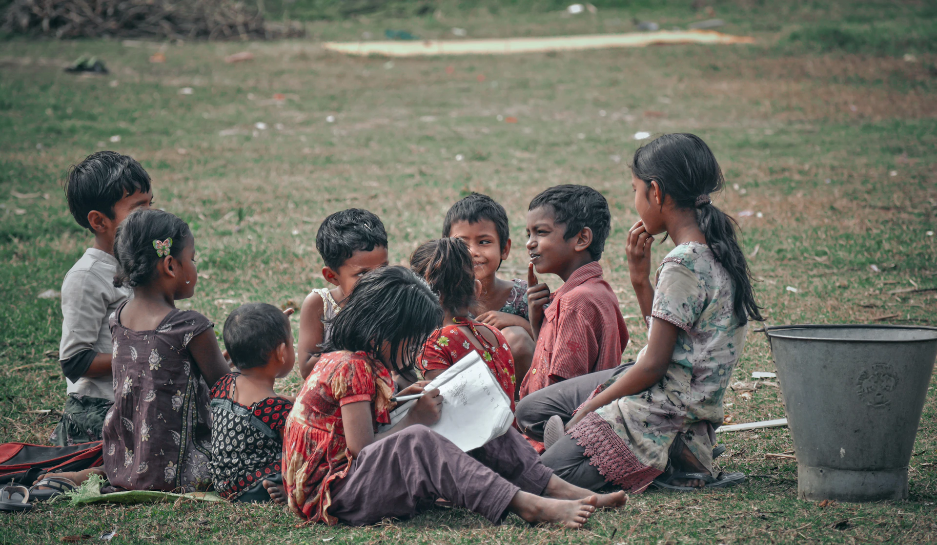 children sitting on green grass field during daytime