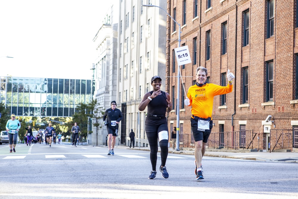 man in orange t-shirt and black shorts running on road during daytime