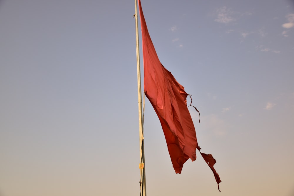 red flag on pole under blue sky during daytime