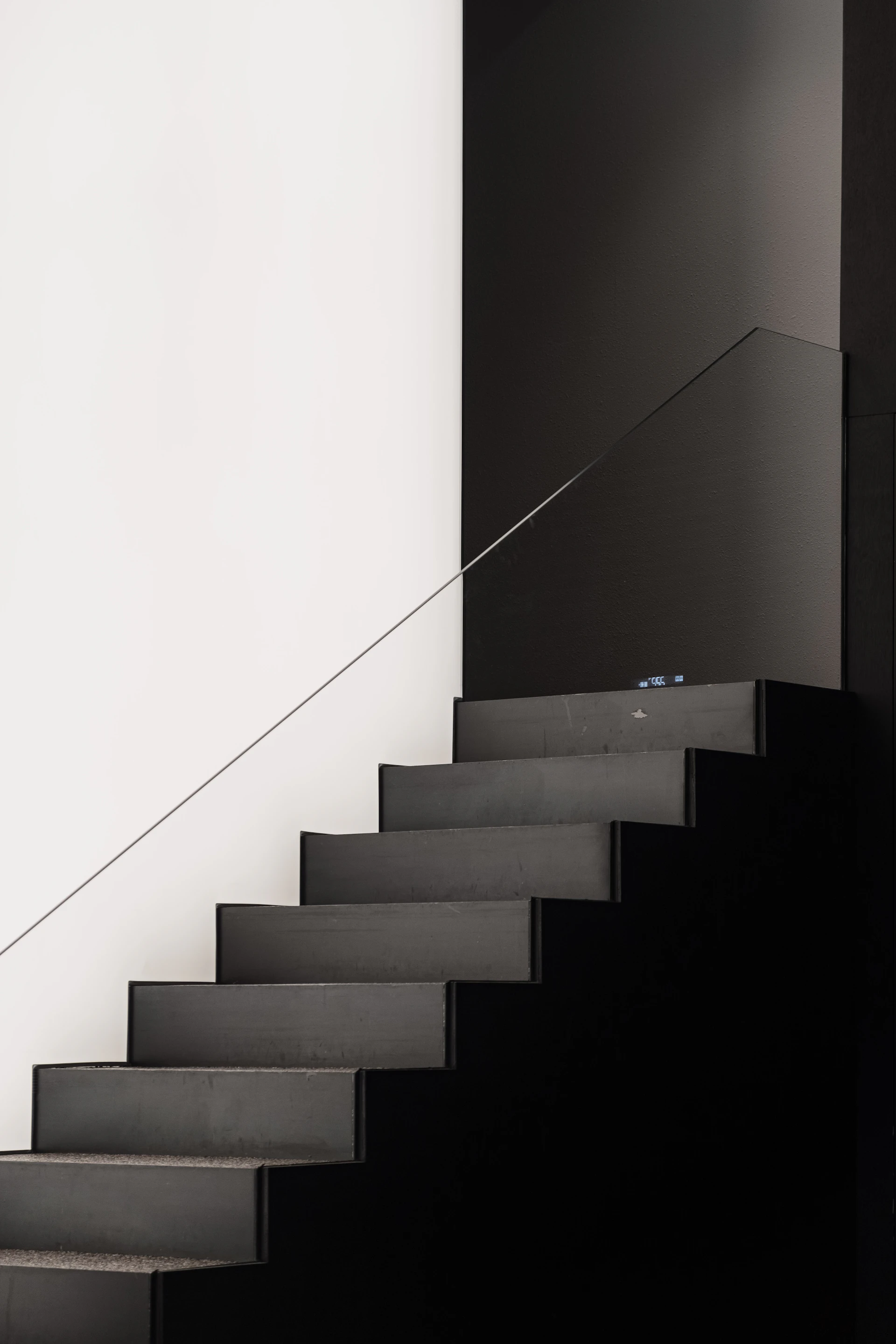 Dark concrete staircase against a white wall