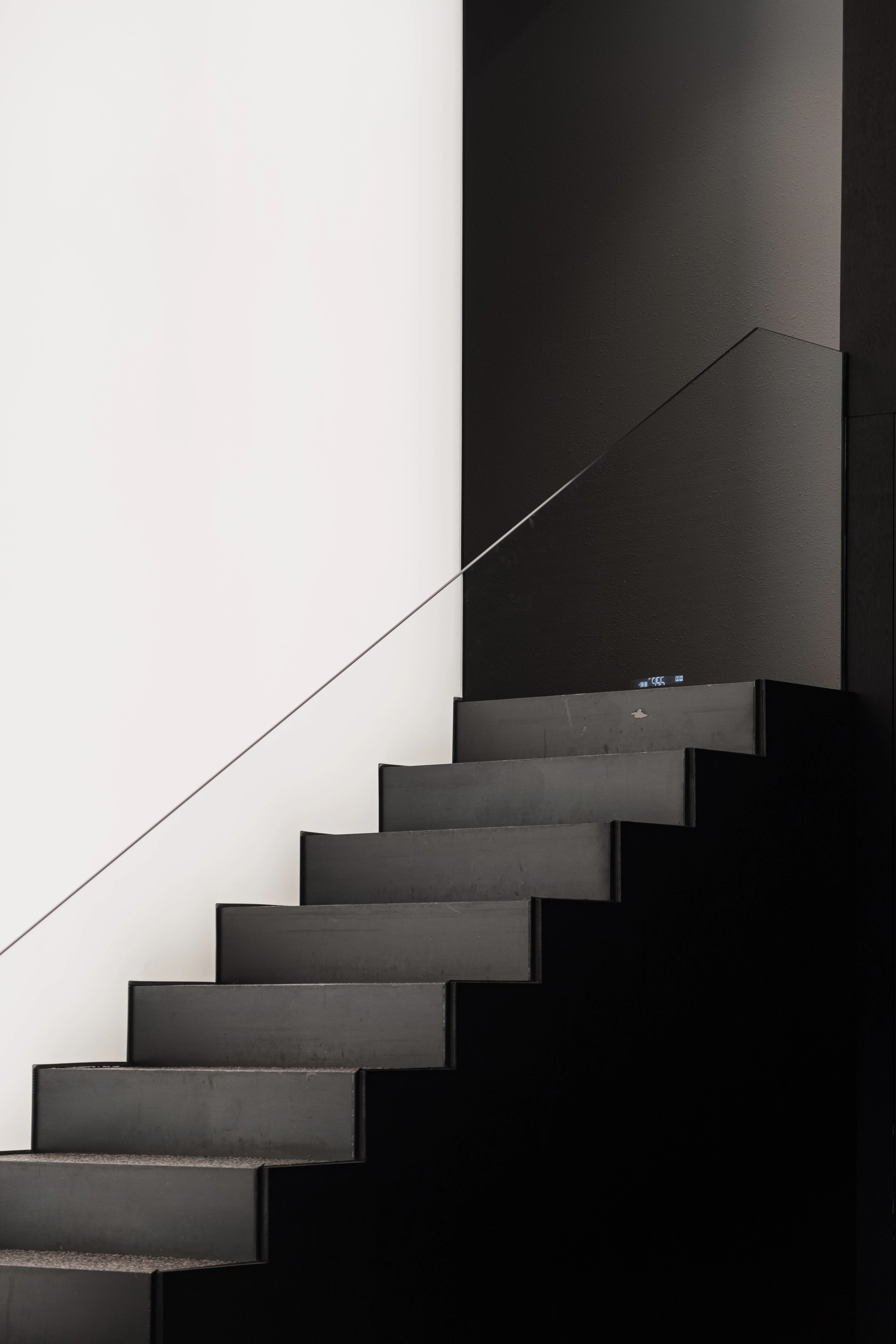 Dark staircase beside a white wall