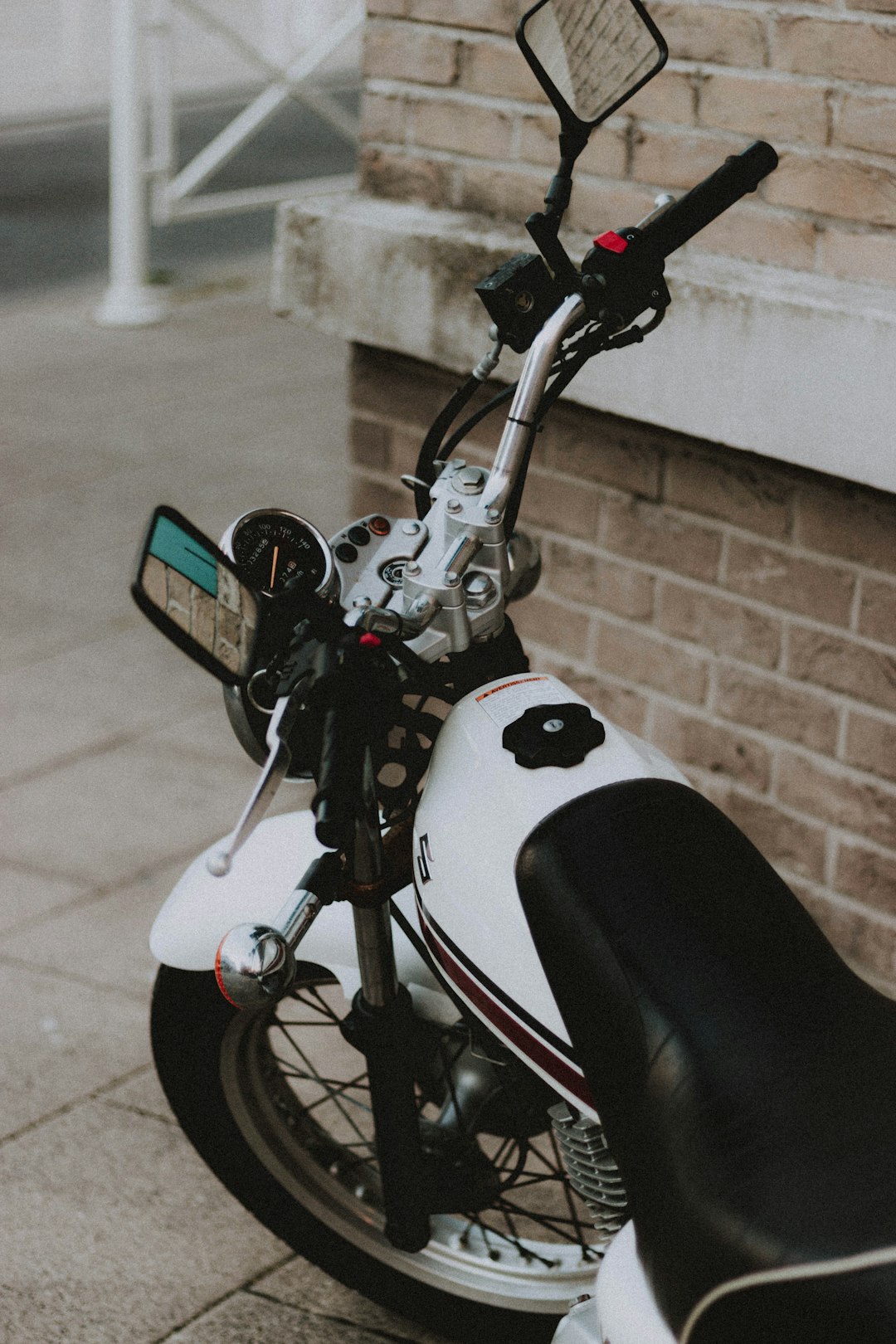 white and black motorcycle parked near brown brick wall