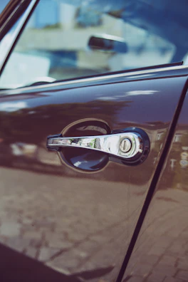 Close-up of a metallic gold car door handle reflecting city lights.