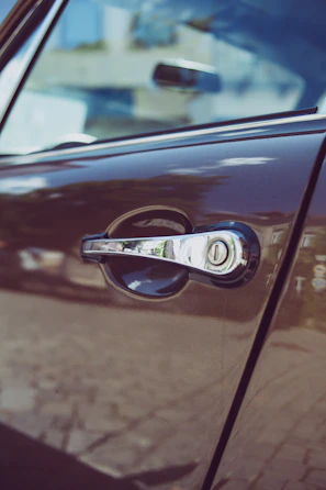 Shiny car door lock with a golden key inserted, reflecting the city lights.