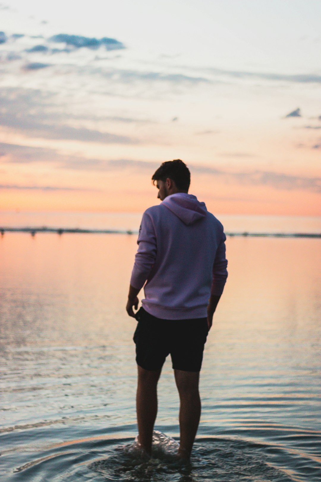 man in gray hoodie standing on body of water during daytime