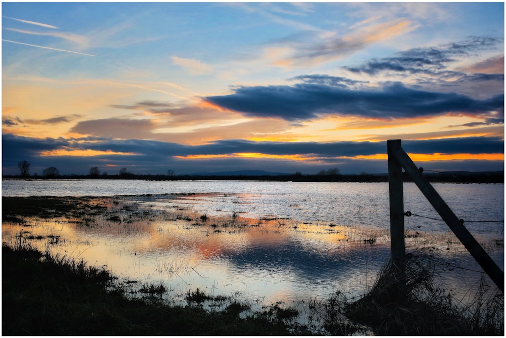 body of water under cloudy sky during sunset