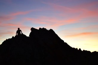 The silhouette of a traveler meditating at dusk, with a vast sky painted in twilight hues.