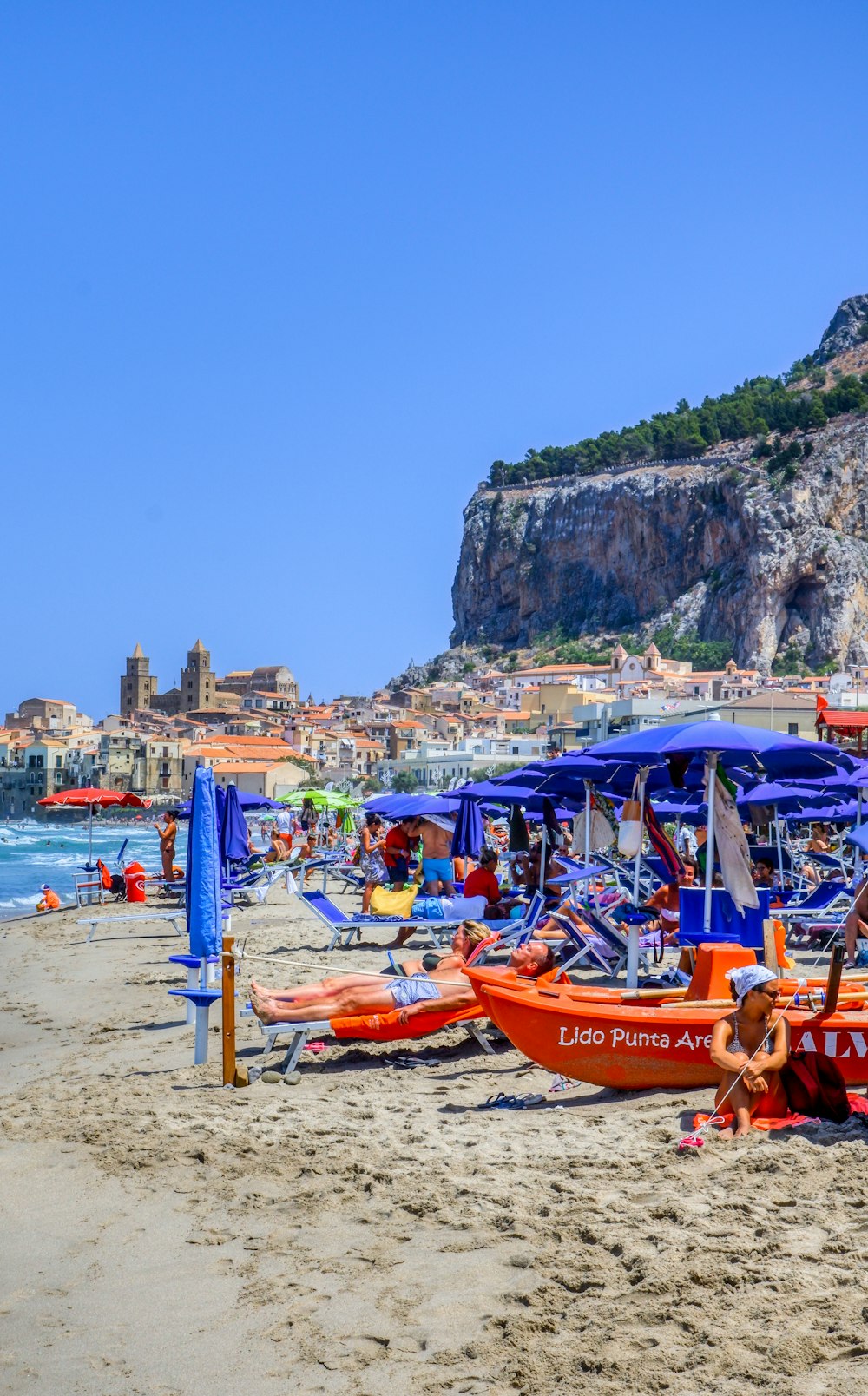 people riding on red boat on beach during daytime