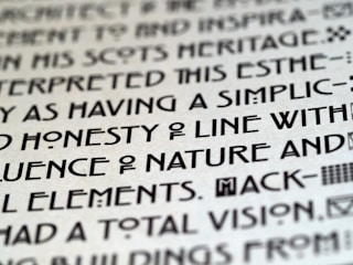 Close-up image of text with a unique, artistic typeface on a light background, featuring bold, geometric characters.