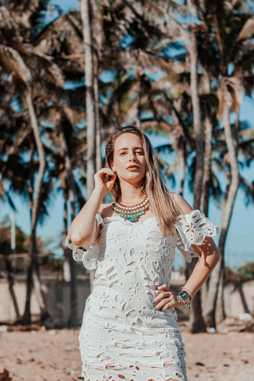 woman in white floral dress standing near trees during daytime