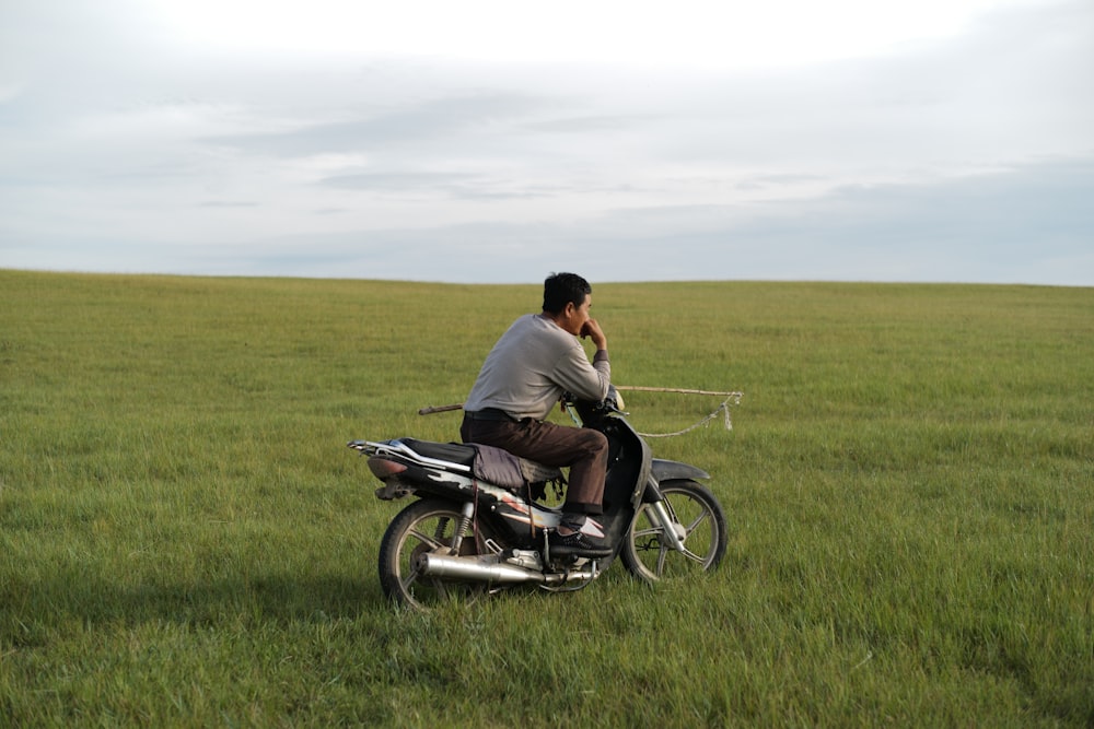 man in black shirt riding motorcycle on green grass field during daytime