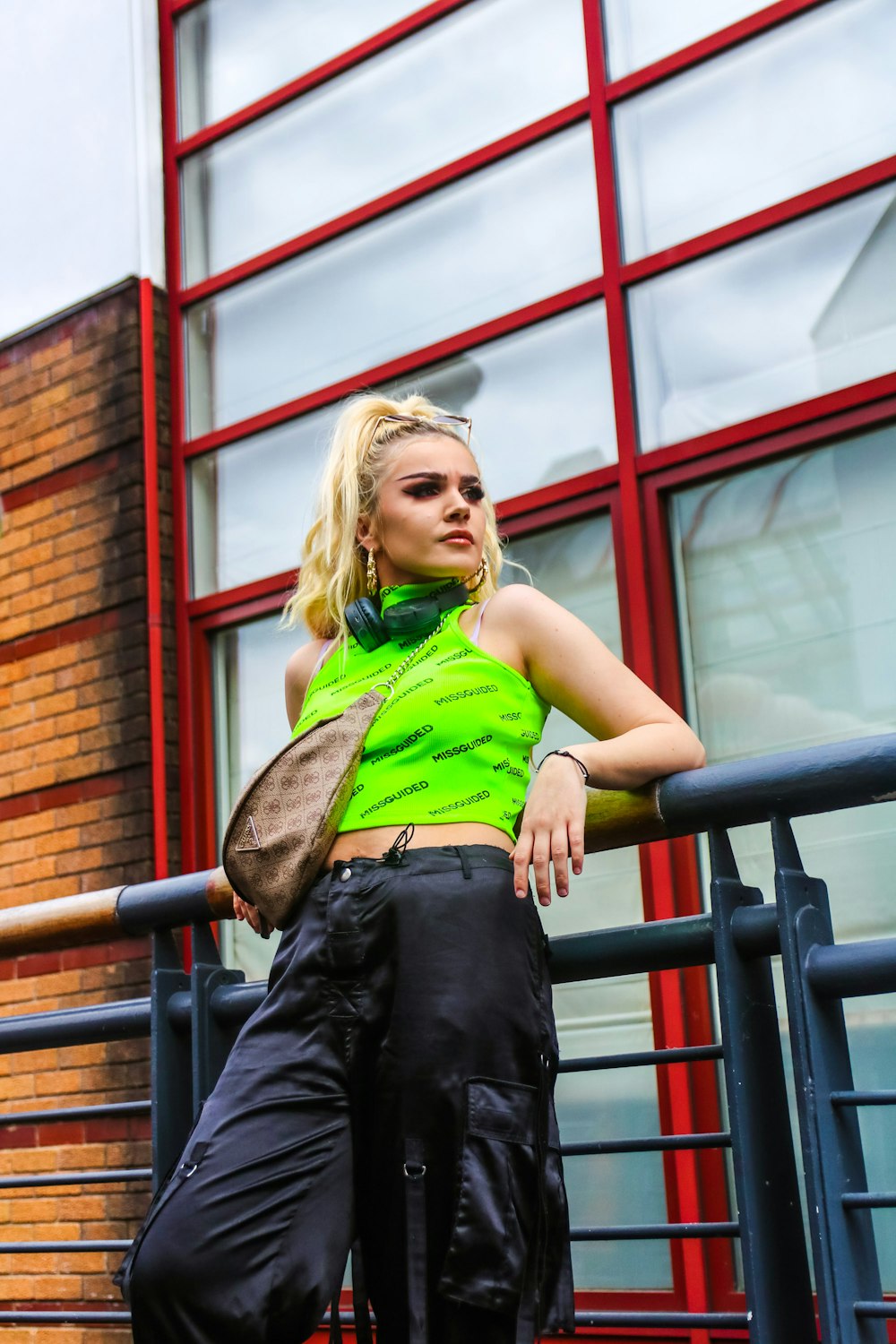 woman in green shirt and black denim jeans sitting on black metal railings