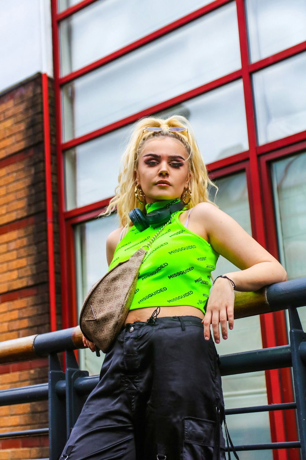 woman in green and black sleeveless shirt and black denim jeans sitting on black metal railings