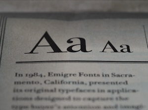 The image displays a close-up of text on a page, showcasing different styles and weights of the letter 'A'. Below the large 'A' letters, there is more printed text in a serif font, detailing historical information about Emigre Fonts in Sacramento, California.