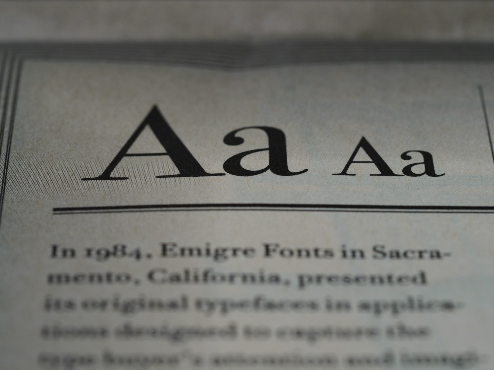 The image displays a close-up of text on a page, showcasing different styles and weights of the letter 'A'. Below the large 'A' letters, there is more printed text in a serif font, detailing historical information about Emigre Fonts in Sacramento, California.