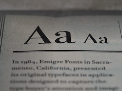 The image displays a close-up of text on a page, showcasing different styles and weights of the letter 'A'. Below the large 'A' letters, there is more printed text in a serif font, detailing historical information about Emigre Fonts in Sacramento, California.