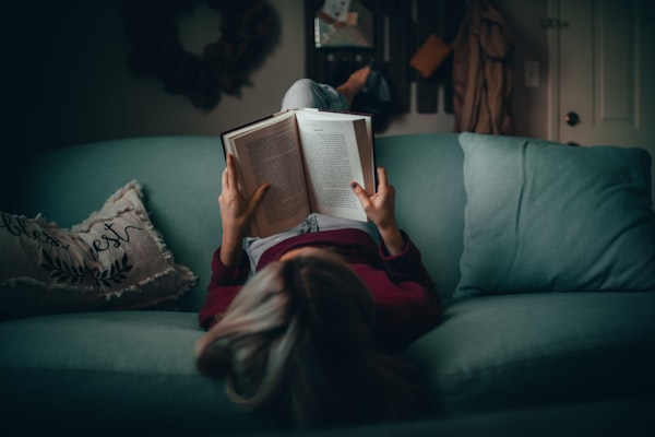 a woman reading a book on a green couch