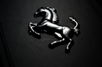 Close-up of a beautifully designed Arabian horse logo in gold on dark background.