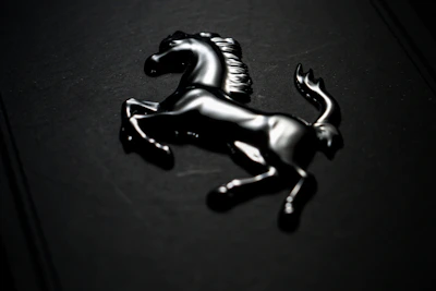 A dynamic shot of a horse motif accessory symbolizing power and progress, set against a deep black backdrop with seigaiha wave patterns.