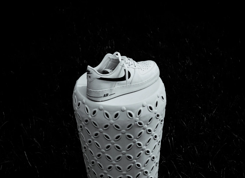 A premium sneaker slowly rotating on a clean white pedestal with a soft gold shimmer sweep highlighting its sleek design.