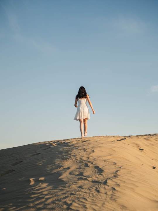 woman in white dress standing on brown sand during daytime in Saskatchewan Canada