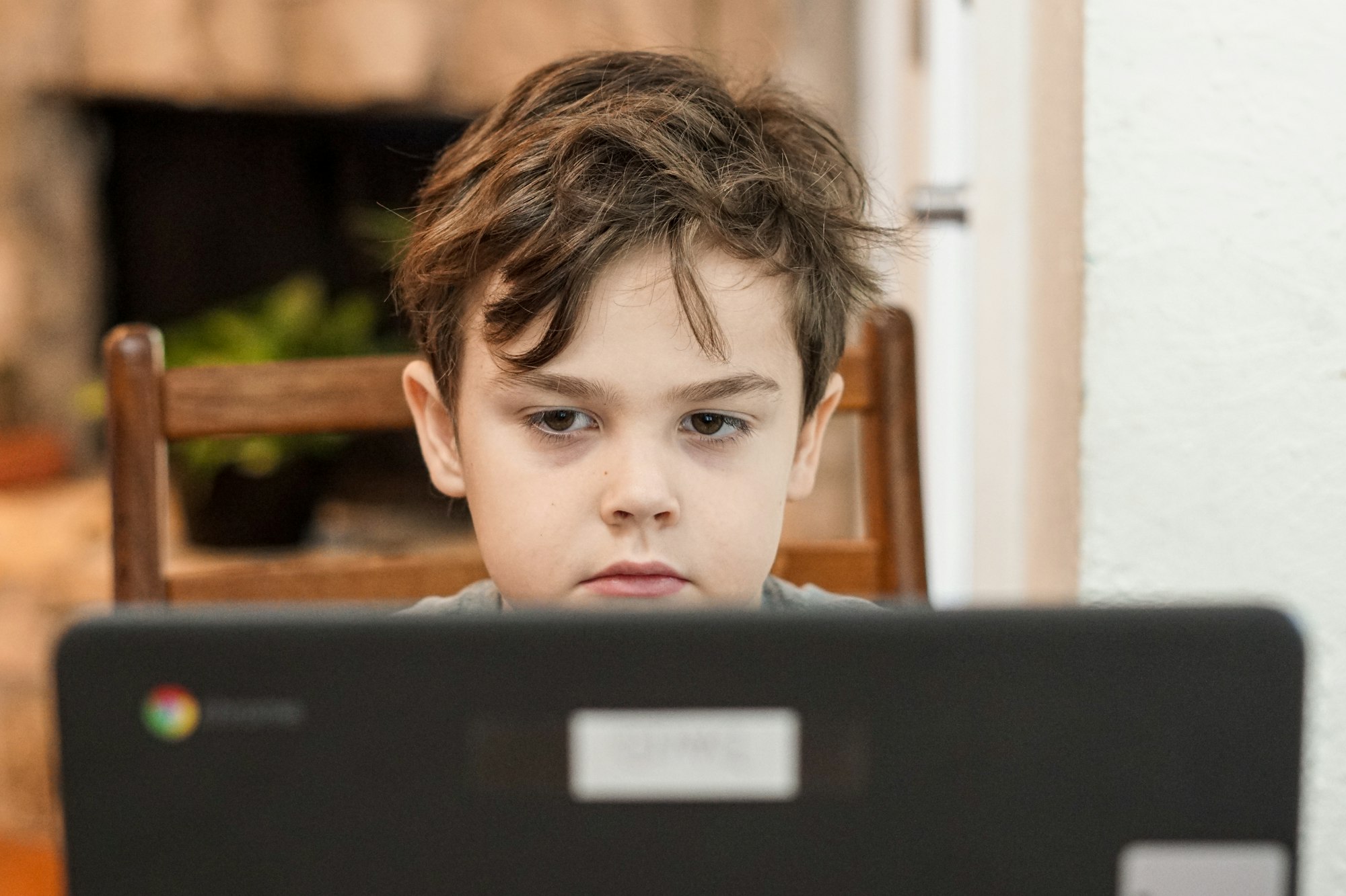 Kindergarten little boy student looking at a laptop computer while participating in distance home learning during coronavirus quarantine. 