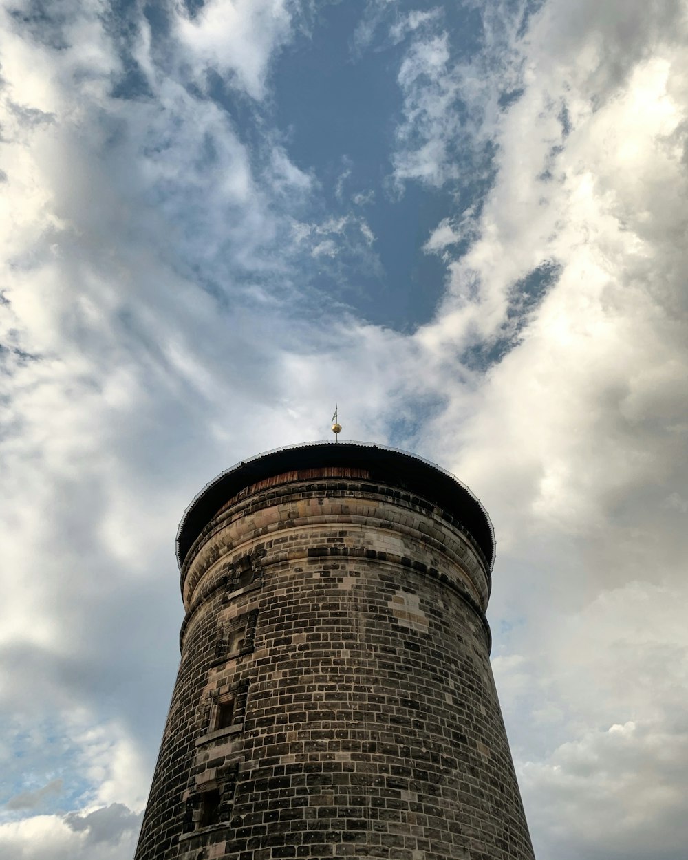 brown concrete tower under white clouds and blue sky during daytime