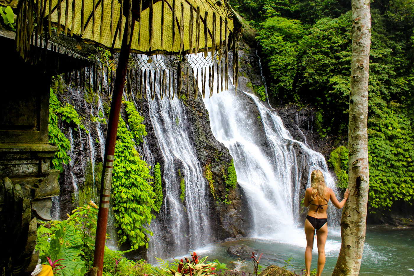 Visitor on a wooden walkway beside the twin waterfalls and pool at Banyumala