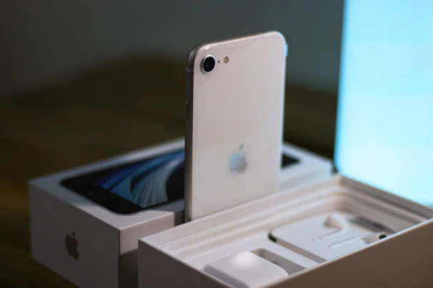 A customer unboxing a new iPhone with excitement in a bright, modern room.