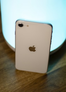 A modern smartphone resting on a white surface with soft blue lighting.
